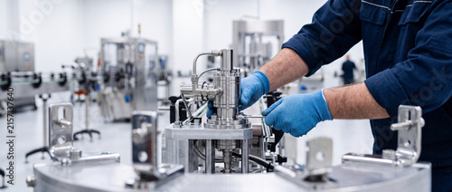 Manufacturing technician adjusting stainless steel machinery on automated production line in modern factory