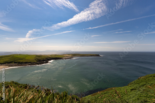 Clear blue sky with wispy clouds above calm sea