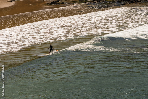 Canvas Print Silhouetted surfer rides gentle ocean wave