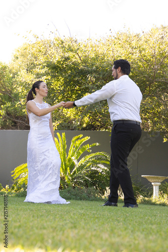 Couple dancing on manicured lawn in private garden with bridal dress and birdbath