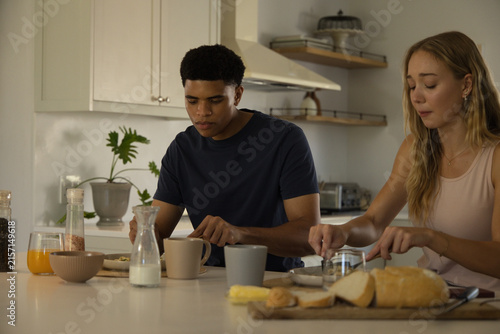 Fotografía Diverse couple preparing breakfast at kitchen island, spreading butter on sliced