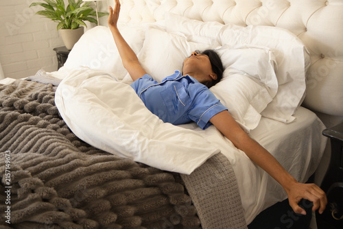 Foto Indian woman reclining on bed wearing light blue pajama top with body pillow and