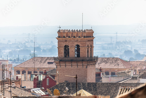 The bell tower of the Church of Santiago el Mayor in Totana, Region of Murcia, Spain, rising above the rooftops 