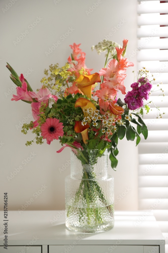 Naklejka premium Bouquet of beautiful summer flowers in vase on cabinet indoors, closeup