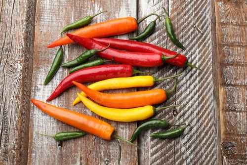 Фотография Fresh chili peppers on color wooden table, flat lay