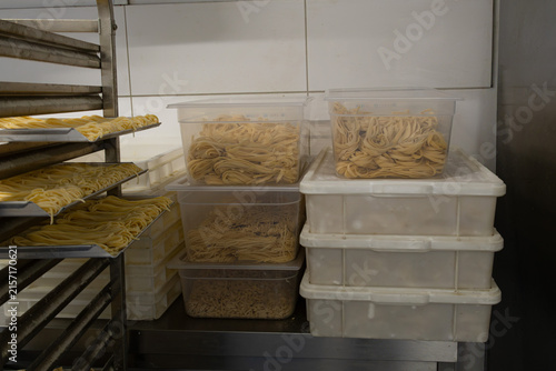 Fresh pasta storage in plastic containers and drying on racks in commercial restaurant kitchen