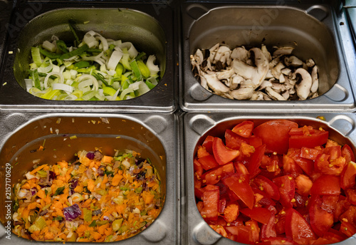 Metal gastronorm containers with prepared fresh vegetables for mise en place in commercial kitchen