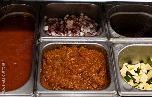 Prepared ingredients in metal gastronorm containers for mise en place in professional restaurant kitchen