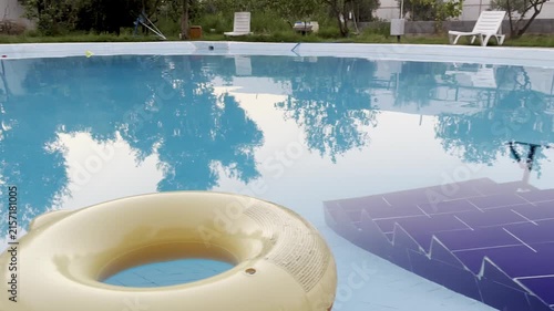 Round blue swimming pool with yellow float and tree reflections
