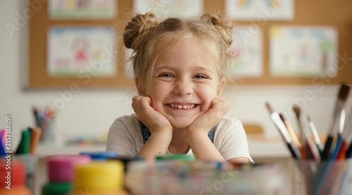 Little girl smiling and resting chin on hands in elementary school art classroom