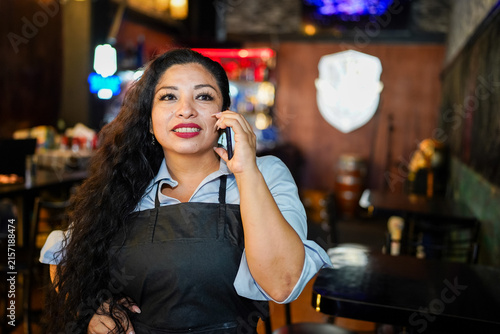 Latin woman entrepreneur managing small business talking on phone