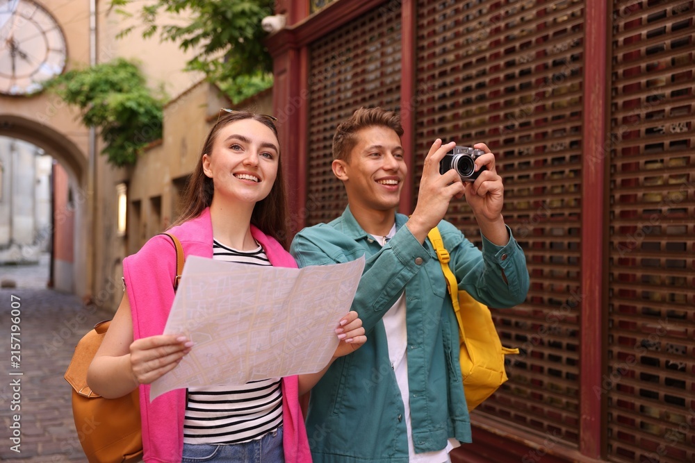 Naklejka premium Travel and tourism. Happy couple with map and camera on city street