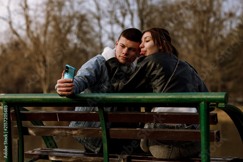 Konstfotografi Couple takes selfie on park bench during cool afternoon surrounded by nature