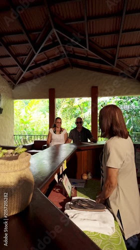 Tourist couple checking in at tropical resort reception desk