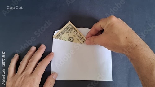 Hand inserting american dollar bill into white paper envelope video motion