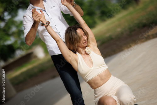 Fotografie Couple dancing outdoors in summer as a woman kneels while her partner supports h