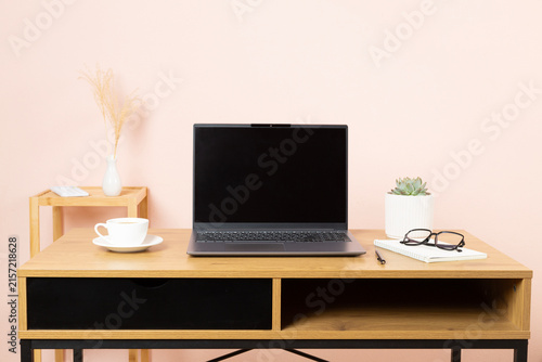 Comfortable workspace with laptop, notebook and flower