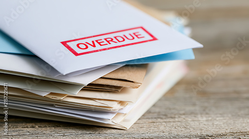 Stack of overdue bills and reminder notices on a rustic wooden table, financial stress, debt, and payment deadlines