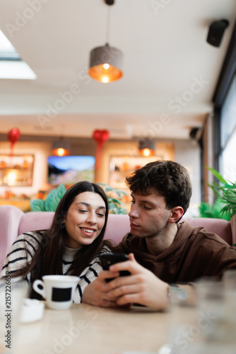 Foto Young couple enjoying time together at a cozy cafe with coffee and smartphones