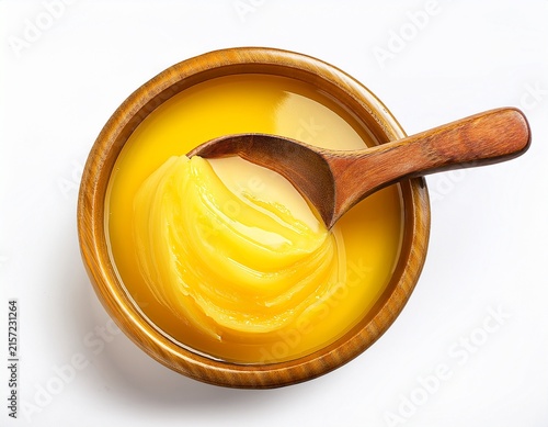 ghee in a golden yellow bowl with a wooden spoon on a white background