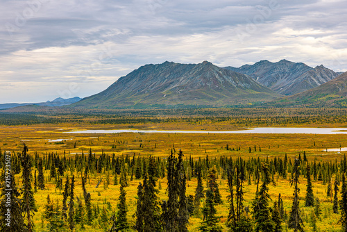 Foto Golden tundra and a still lake stretch toward rugged mountains along the Glenn Highway in Alaska