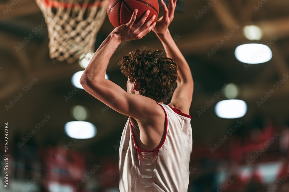 Fototapeta premium Curly-haired Basketball Player in Action, Hoop in Background