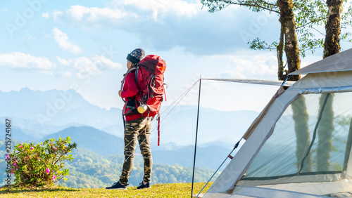 Photography Asian mature woman with backpack standing beside camping tent on mountain viewpo