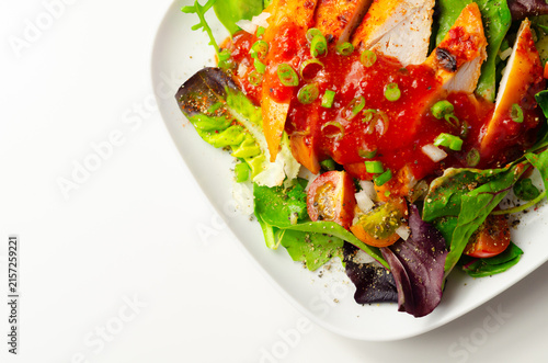 Grilled chicken slices sit atop fresh greens