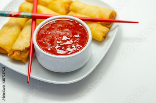 Golden spring rolls rest on a white plate