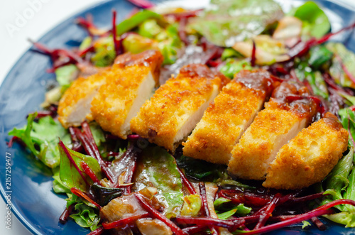 Golden-brown breaded cutlet rests on vibrant salad greens