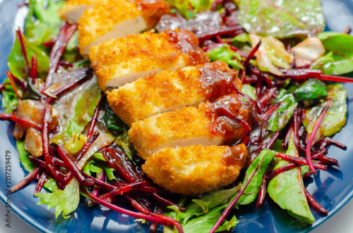 Golden-brown breaded cutlet rests on vibrant salad greens
