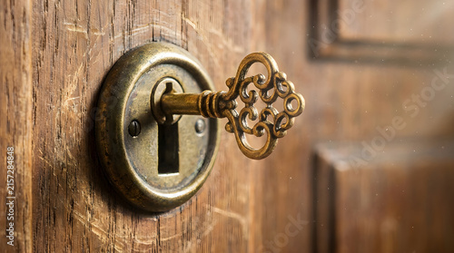 ornate antique key inserted in keyhole on rustic wooden door
