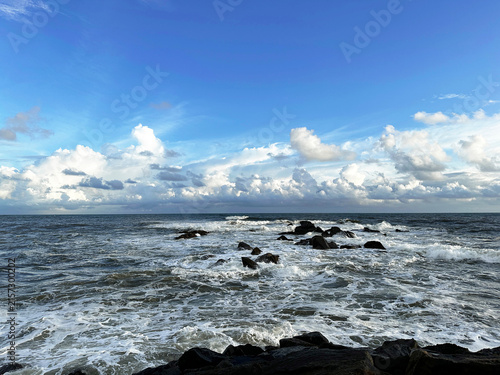 Blue Ocean Waves with Rocky Shoreline Under Cloudy Sky Natural Coastal Seascape