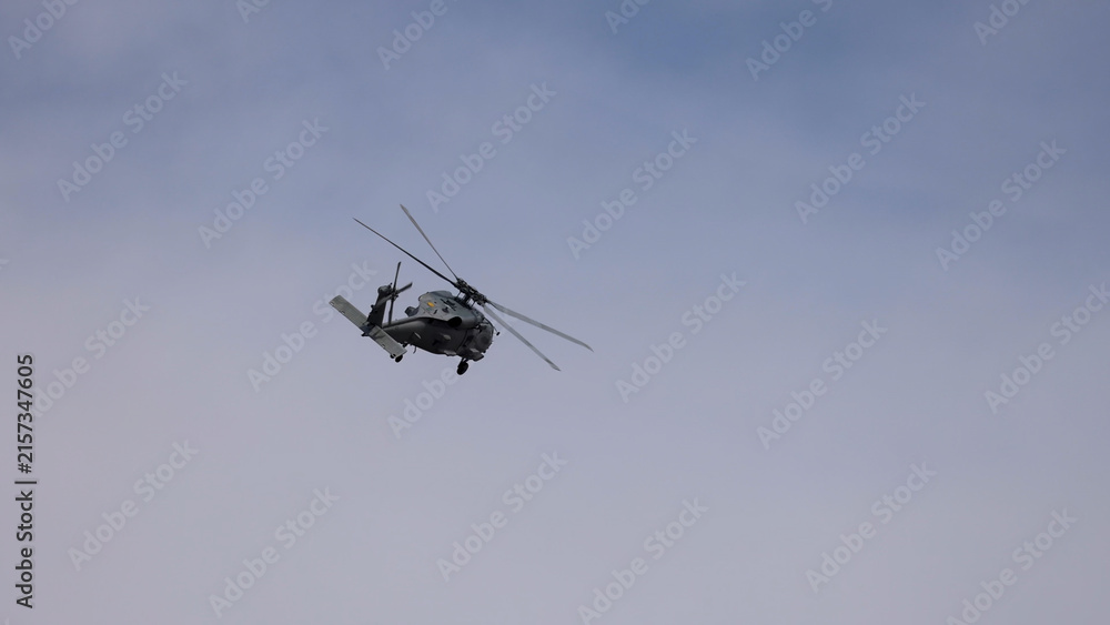 Fototapeta premium Military Helicopter Performing Aerial Maneuvers Against a Cloudy Sky