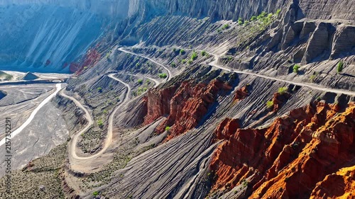 Aerial view of a winding road curving through a steep and colorful mountain canyon in Anjihai Grand Canyon, Xinjiang, China.