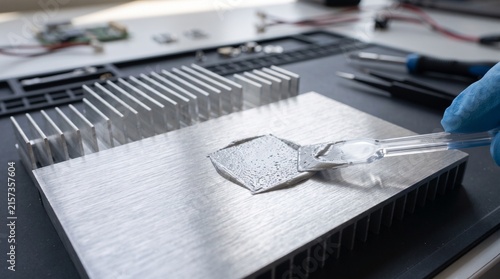 Technician applying thermal paste to a computer heatsink for cooling system maintenance.
