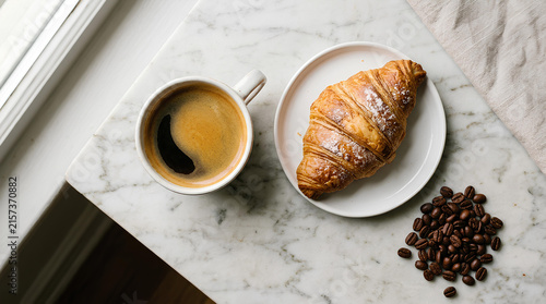 Coffee cup and croissant on a marble table