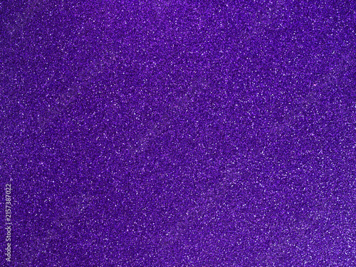 Purple glitter texture. Shiny sparkling violet background. Bright grainy surface with light reflections. Festive abstract pattern for creative design.