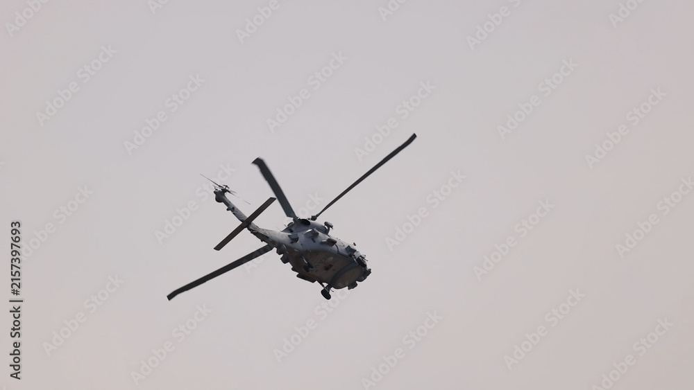 Fototapeta premium Military Helicopter Performing Dynamic Aerial Maneuvers Against a Cloudy Sky