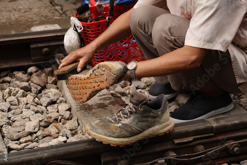 Hombre limpiando botas sobre las vías del tren en Hanoi, Vietnam