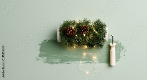 Festive paint roller adorned with greenery, pinecones, and twinkling lights