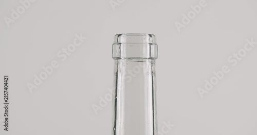 Slow motion close-up of a sommelier using a corkscrew to pull a natural cork stopper from a clear glass bottle, isolated on a clean white background, representing celebration and service