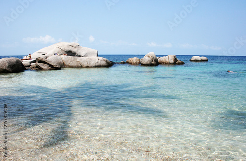 Granite rock formations in shallow crystal clear sea water on a tropical island beach