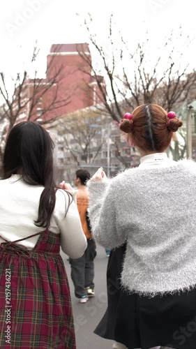 Two Young Women Walking Through Harajuku District in Tokyo Japan