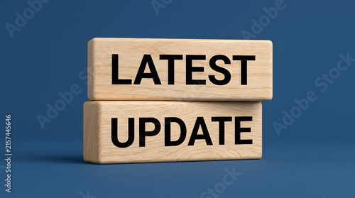 Two light-colored wooden blocks with the words LATEST and UPDATE printed in bold black letters stacked on a solid dark blue background featuring text, message, concept, business and technology