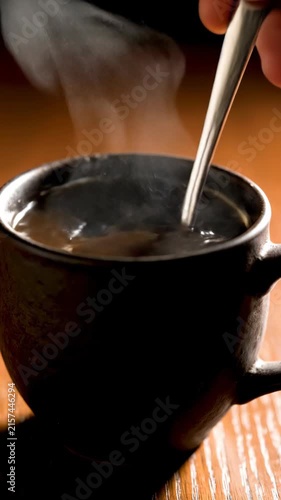 Steam rising from a cup of hot beverage with a spoon stirring it