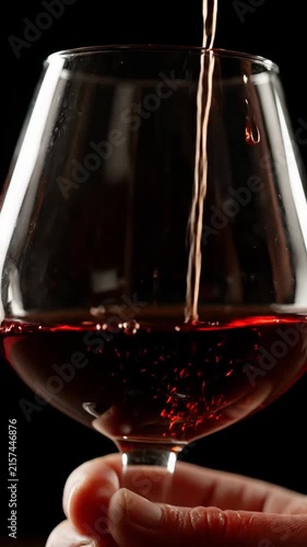 Pouring red wine into a glass, close up of liquid splashing and swirling.