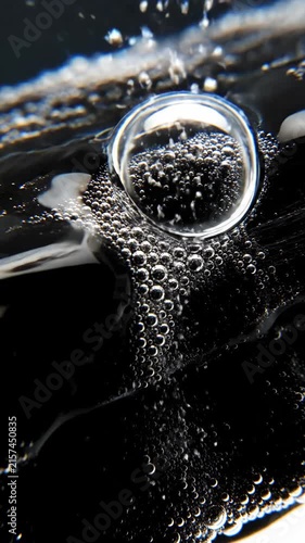 Close-up of bubbles forming in dark liquid, abstract macro view