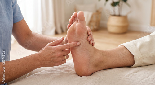 Close-up of a healthcare professional or reflexology therapist hands examining and touching the sole of a patient's foot. Concept of foot health, podiatry, and physical therapy.