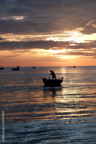 Foto Silhouetted view of local fishermen and coracles on the ocean under a glowing mo